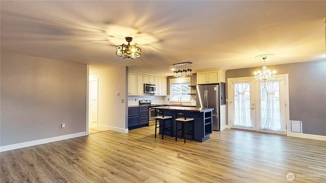 kitchen with a kitchen bar, light wood-style floors, appliances with stainless steel finishes, and an inviting chandelier