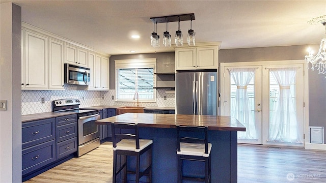 kitchen featuring wooden counters, a sink, stainless steel appliances, french doors, and blue cabinets