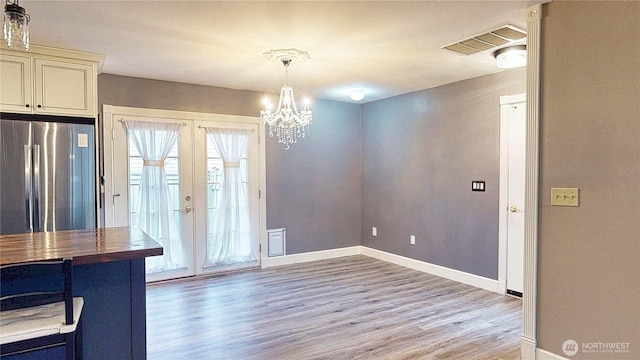 unfurnished dining area with baseboards, french doors, visible vents, and light wood-type flooring