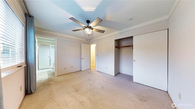 unfurnished bedroom featuring ceiling fan, a closet, ensuite bathroom, light carpet, and crown molding