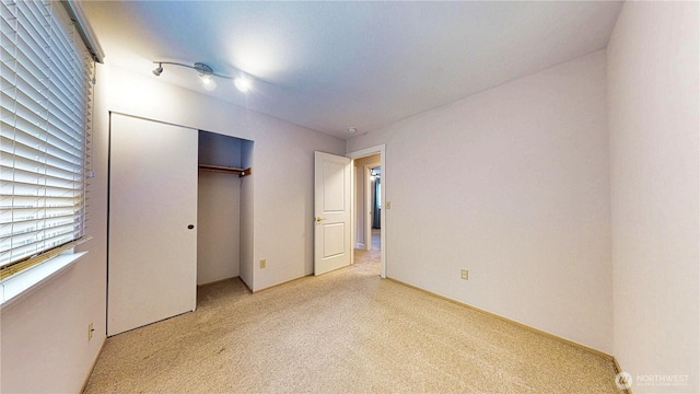 unfurnished bedroom featuring a closet and light colored carpet