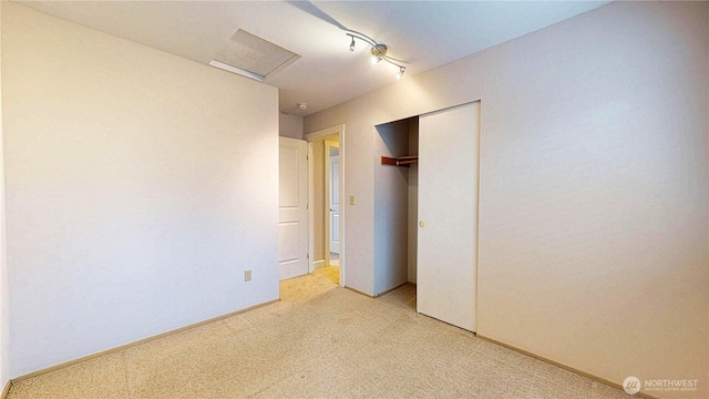 unfurnished bedroom featuring attic access, baseboards, a closet, and light carpet