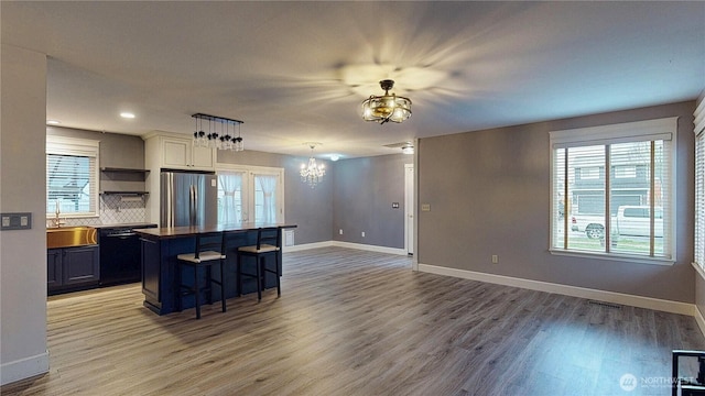 kitchen with dark countertops, dishwasher, a breakfast bar area, freestanding refrigerator, and a sink