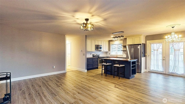 kitchen with a center island, a kitchen bar, light wood-style flooring, an inviting chandelier, and stainless steel appliances