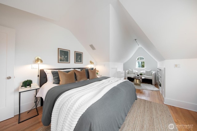 bedroom with baseboards, lofted ceiling, and wood finished floors