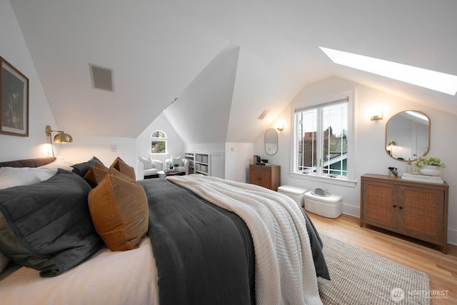 bedroom featuring lofted ceiling with skylight, visible vents, and light wood finished floors