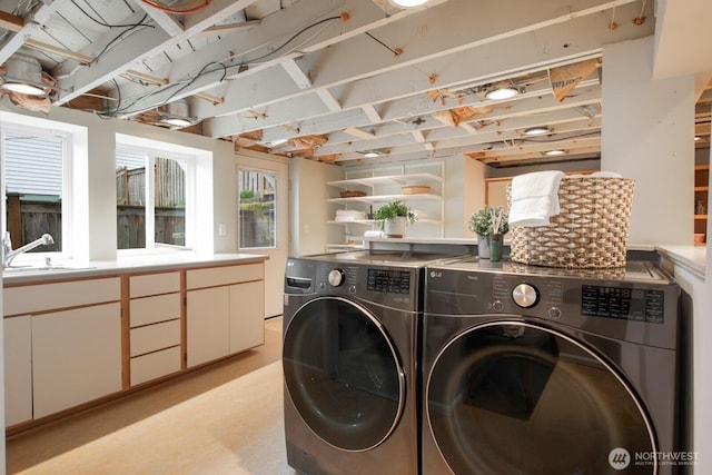 laundry area with cabinet space, separate washer and dryer, and a sink