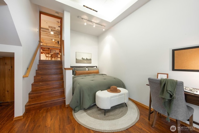 bedroom with wood finished floors, visible vents, baseboards, a skylight, and rail lighting