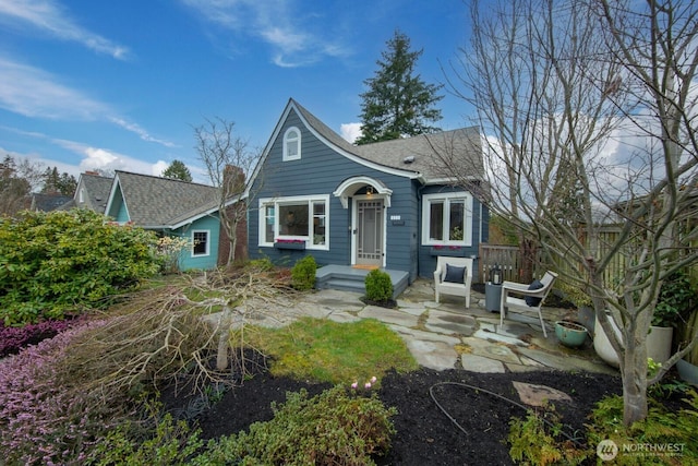 view of front of property with roof with shingles and a patio area