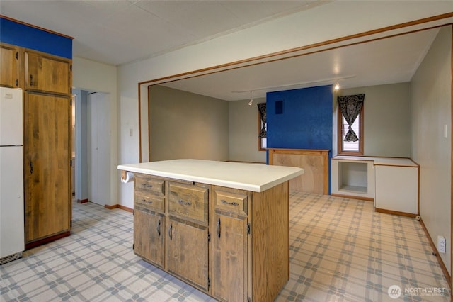 446 Eklund Ave, Hoquiam, WA 98550 - kitchen featuring light countertops, a kitchen island, freestanding refrigerator, brown cabinets, and baseboards