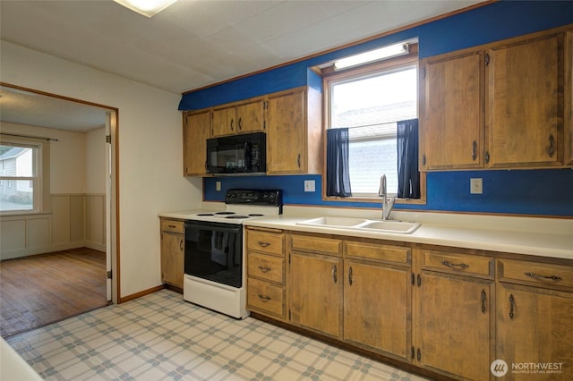 446 Eklund Ave, Hoquiam, WA 98550 - kitchen with light countertops, range with electric cooktop, a sink, black microwave, and a healthy amount of sunlight