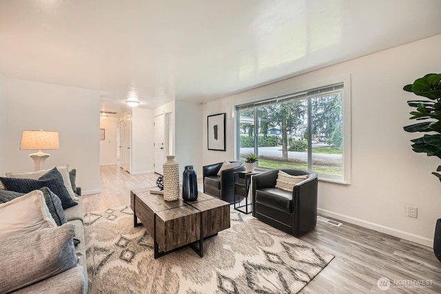 living room featuring light wood-style flooring, baseboards, and visible vents