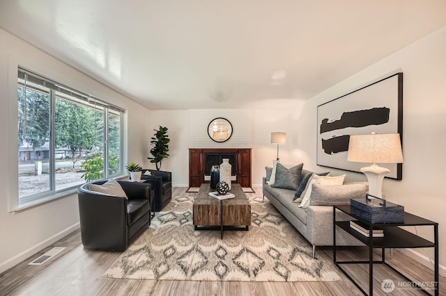 living area featuring visible vents, baseboards, wood finished floors, and a fireplace