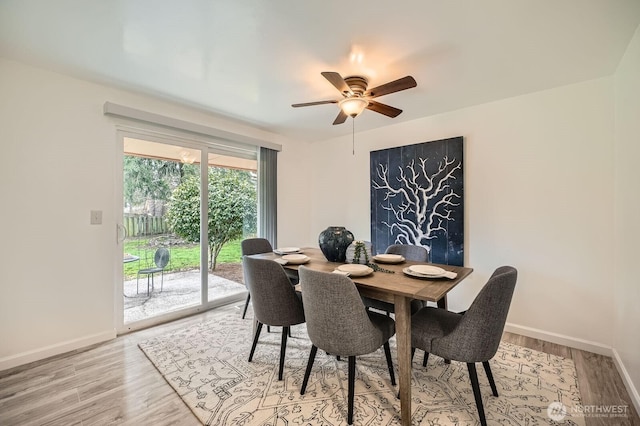 dining space featuring baseboards, light wood-style floors, and a ceiling fan