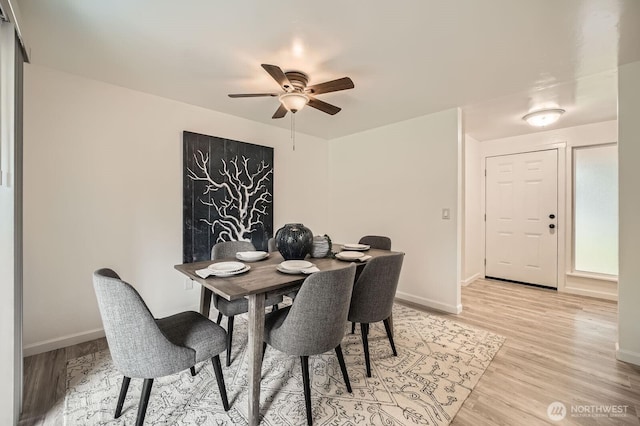 dining room with light wood finished floors, baseboards, and ceiling fan