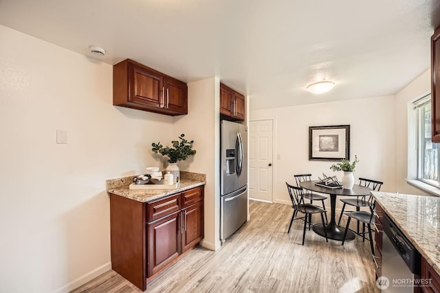 kitchen with light wood-style flooring, appliances with stainless steel finishes, baseboards, and light stone countertops