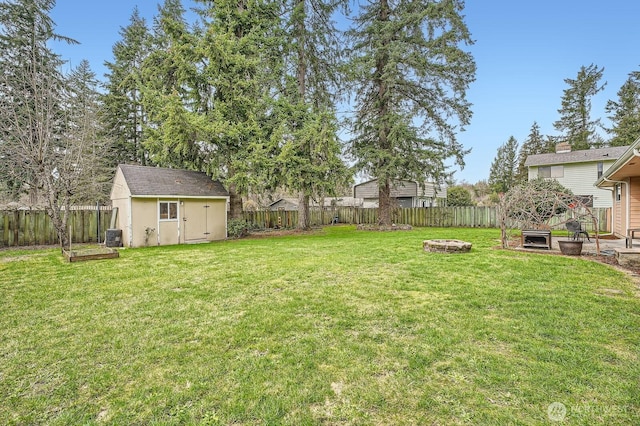 view of yard featuring an outdoor fire pit, a fenced backyard, and an outdoor structure