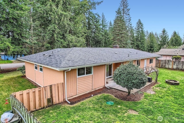 ranch-style home with a front lawn, fence, roof with shingles, and a chimney