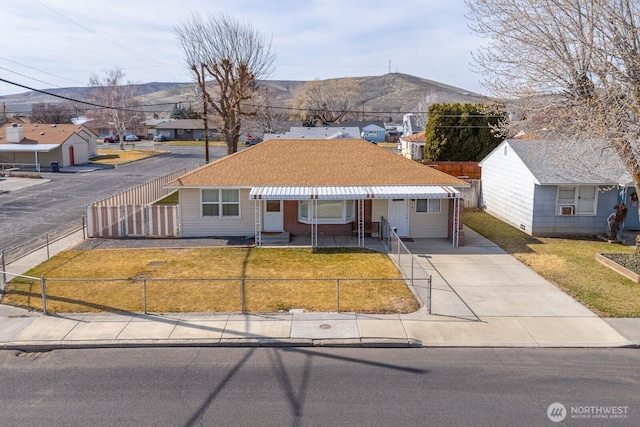 ranch-style home featuring a front yard, a mountain view, brick siding, a fenced front yard, and a residential view