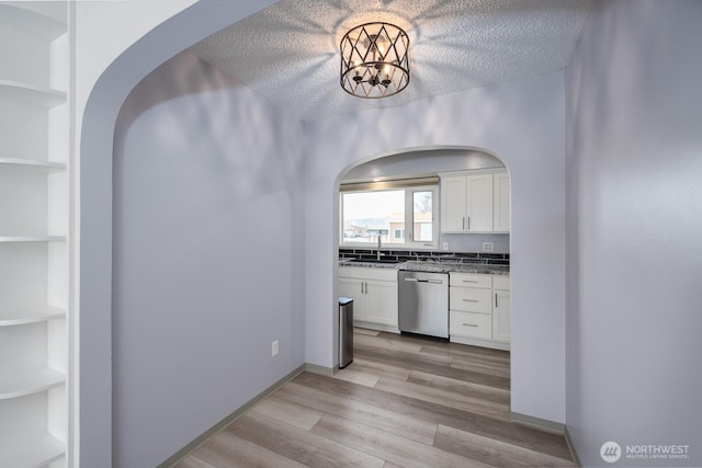 kitchen with open shelves, a sink, white cabinetry, light wood finished floors, and dishwasher