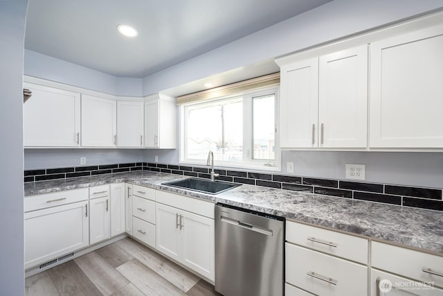 kitchen with visible vents, dishwasher, light wood-style flooring, white cabinets, and a sink