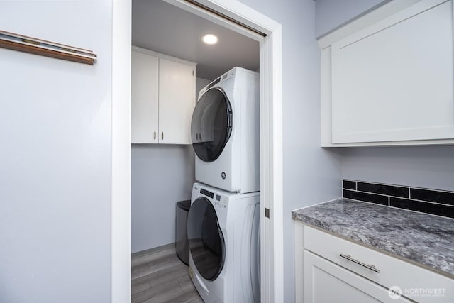 laundry room with recessed lighting, stacked washer / drying machine, cabinet space, and light wood-style flooring