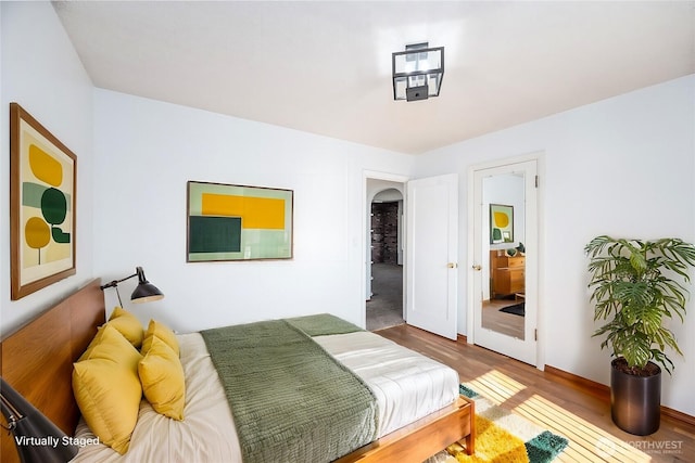 bedroom featuring arched walkways and wood finished floors