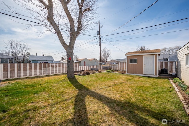 view of yard with an outdoor structure, a fenced backyard, and a shed