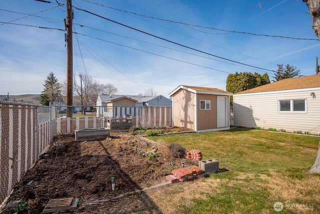 view of yard with an outdoor structure, a storage unit, a fenced backyard, and a garden