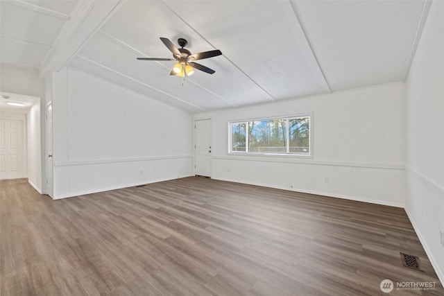 empty room with lofted ceiling with beams, wood finished floors, visible vents, and ceiling fan