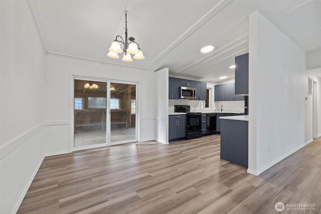 kitchen featuring black appliances, light countertops, light wood-style floors, blue cabinets, and a chandelier