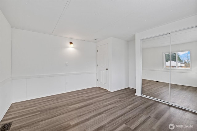 unfurnished bedroom featuring wood finished floors, visible vents, and a closet