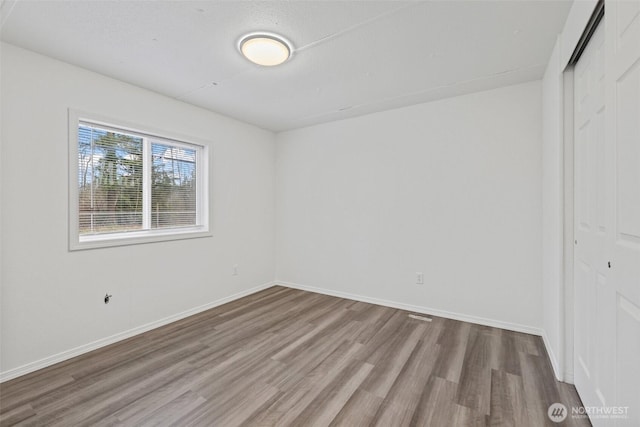 unfurnished bedroom with wood finished floors, a closet, and baseboards