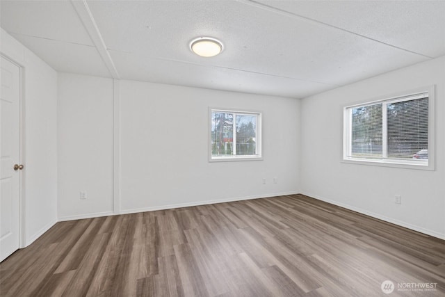 empty room with wood finished floors, baseboards, and a textured ceiling