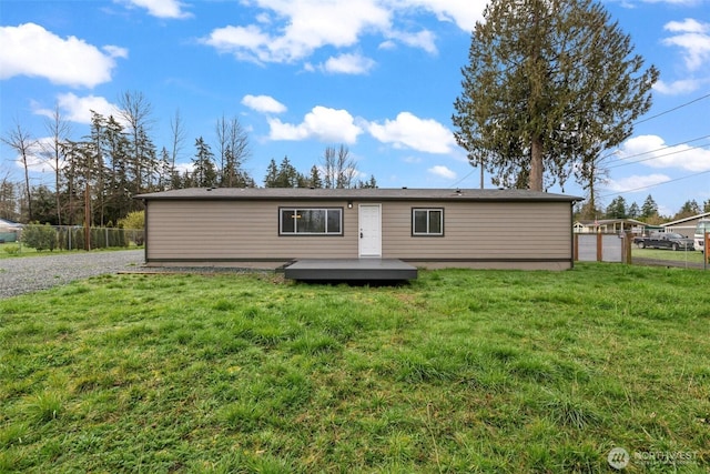 rear view of property featuring a yard, a deck, and fence