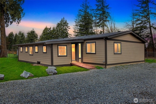 view of front of property with gravel driveway, a yard, and fence