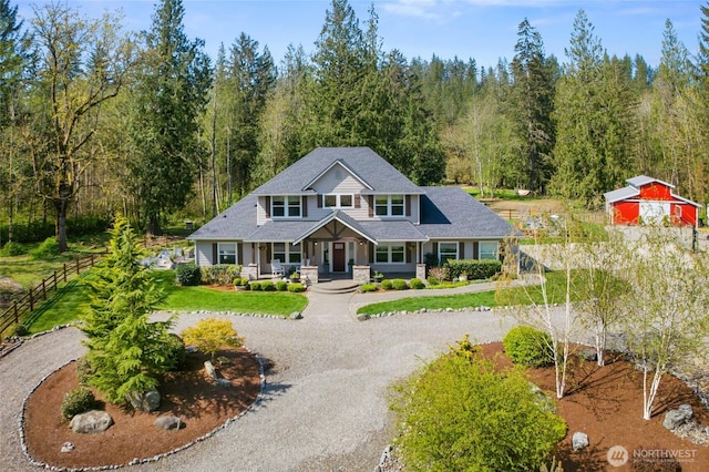 craftsman-style house with fence, curved driveway, a porch, and a forest view