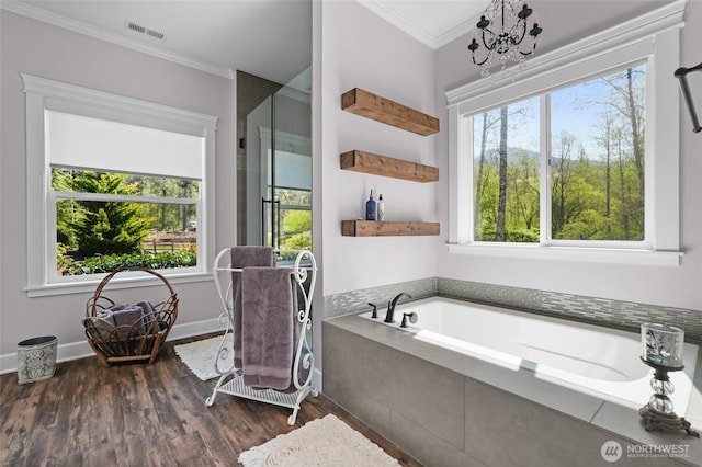 full bath featuring visible vents, crown molding, wood finished floors, and a tub