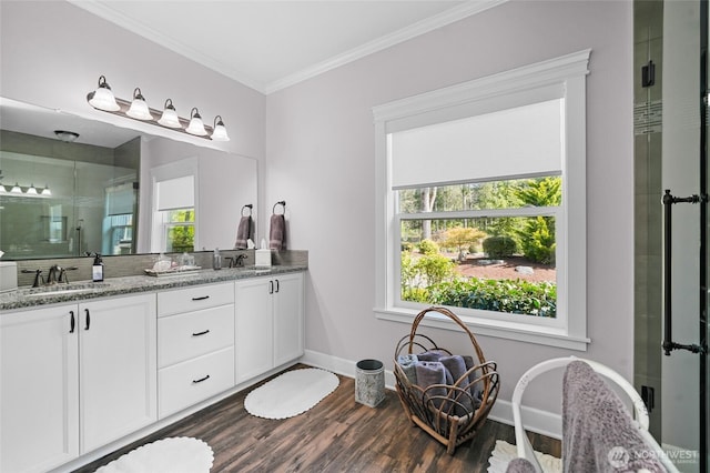 full bath with crown molding, a sink, double vanity, a shower stall, and wood finished floors