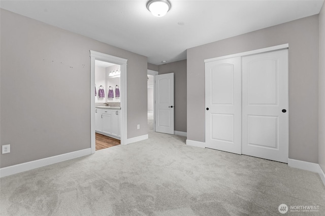 unfurnished bedroom with a closet, carpet flooring, baseboards, and a sink