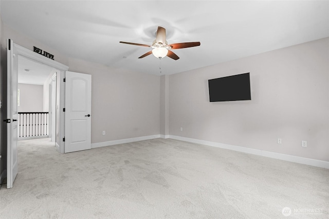 spare room with baseboards, a ceiling fan, and light carpet