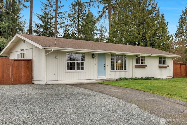 single story home with roof with shingles, gravel driveway, a front yard, and fence