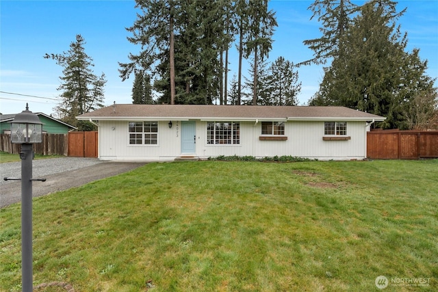 single story home with aphalt driveway, fence, and a front yard