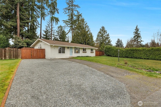 single story home with a front lawn, driveway, and fence