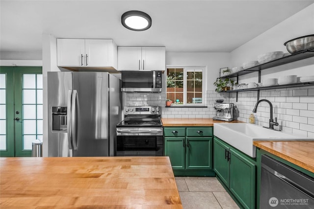 kitchen with green cabinets, a sink, stainless steel appliances, and butcher block counters