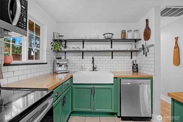 kitchen with visible vents, a sink, stainless steel appliances, green cabinets, and butcher block counters