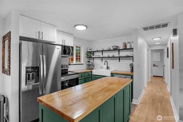 kitchen with stainless steel appliances, wooden counters, and green cabinetry