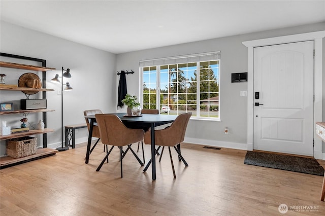 dining space featuring light wood-style flooring, baseboards, and visible vents