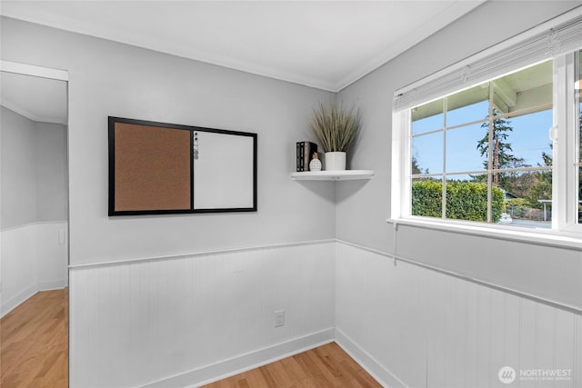 unfurnished room featuring ornamental molding, light wood finished floors, and wainscoting