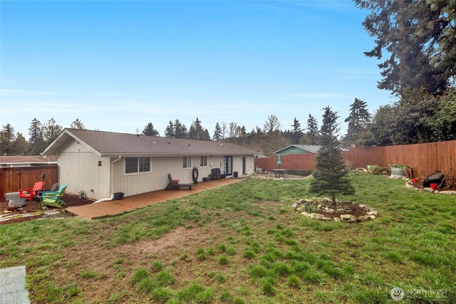 rear view of property with a wooden deck, a lawn, and a fenced backyard